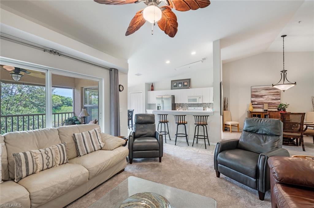 Living room with a ceiling fan, light carpet, vaulted ceiling, and recessed lighting