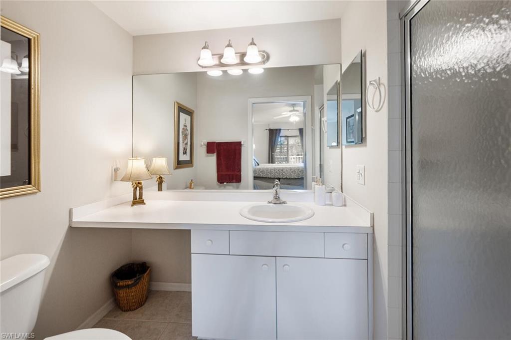 Full bathroom with vanity, connected bathroom, light tile patterned floors, an enclosed shower, and a ceiling fan