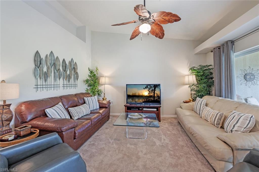 Living area featuring a ceiling fan, carpet flooring, and lofted ceiling