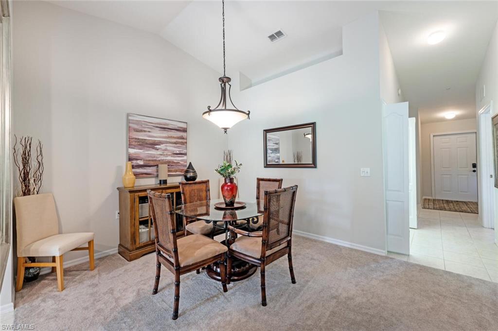 Dining space with light carpet, high vaulted ceiling, and light tile patterned floors