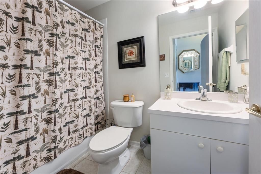 Bathroom with light tile patterned floors, vanity, and shower / bath combo with shower curtain