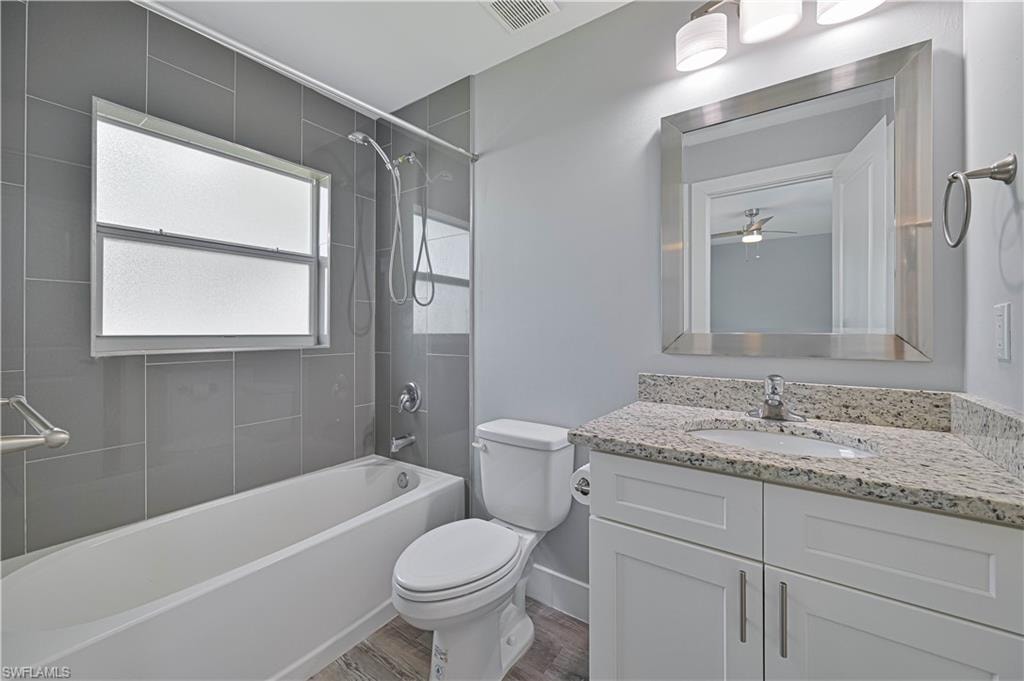 Private en-suite bathroom featuring a granite vanity, tiled tub/shower combination, modern fixtures, and a bright window for natural light.