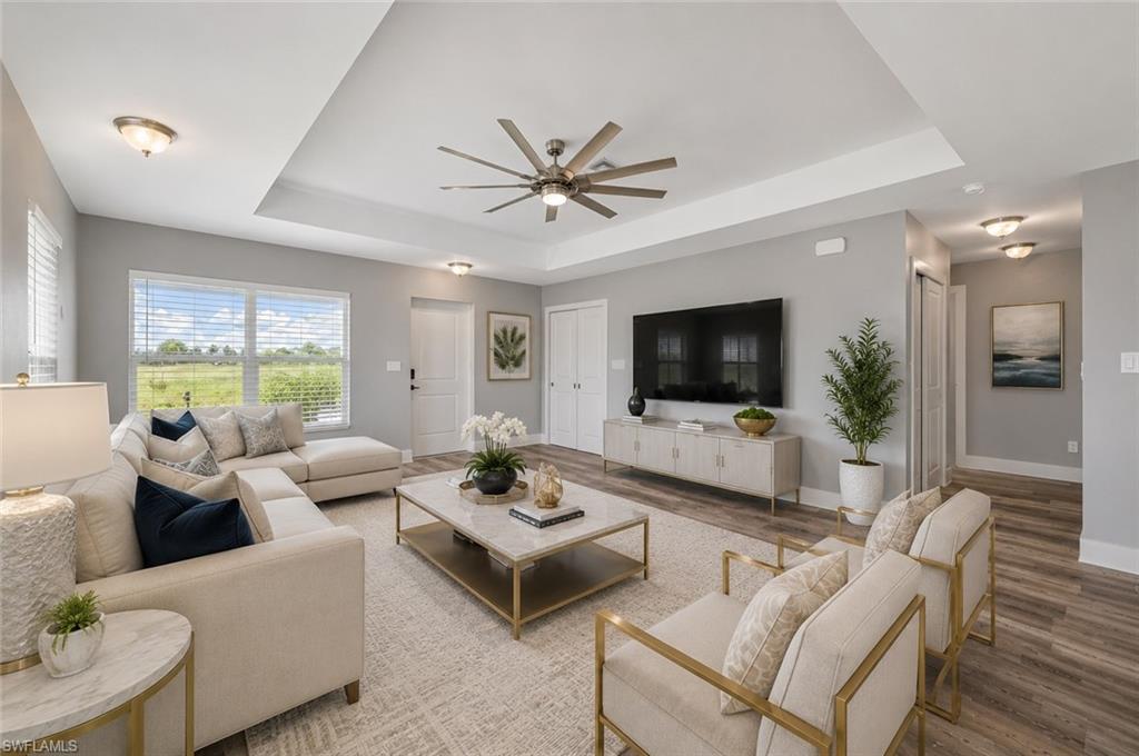 Inviting great room with dramatic tray ceilings, oversized windows, luxury vinyl plank flooring, and an open layout designed for comfortable living and effortless entertaining. [Virtually Staged]
