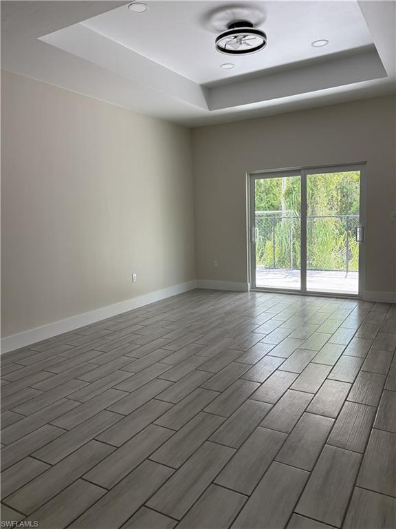 Recessed lighting, tray ceiling, integrated ceiling fan, light wood-finish tile flooring, and sliding glass door