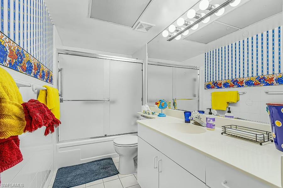 Vanity with integrated sink, white cabinetry, mirrored wall, and overhead vanity lighting