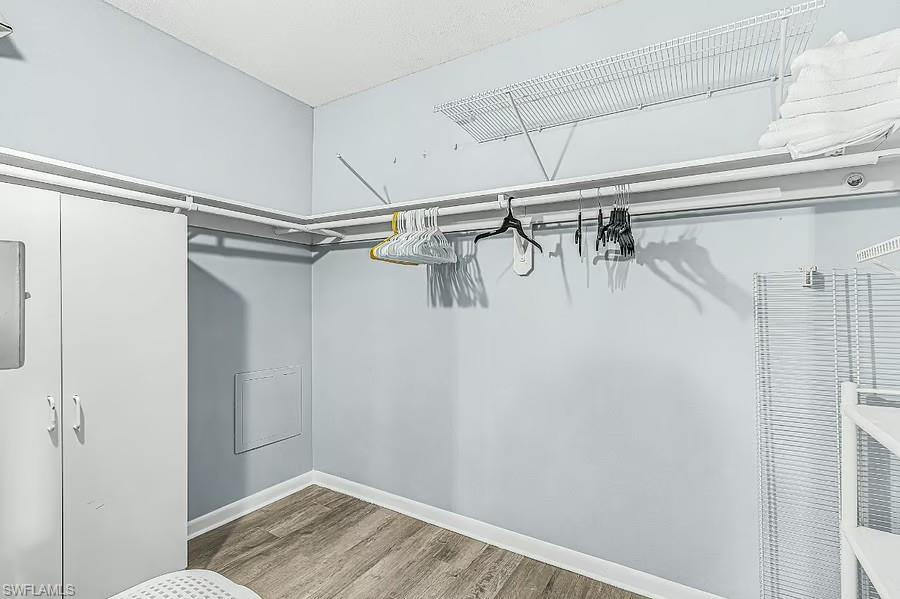 Wood-finish flooring, built-in shelving, white cabinetry, and overhead wire racks