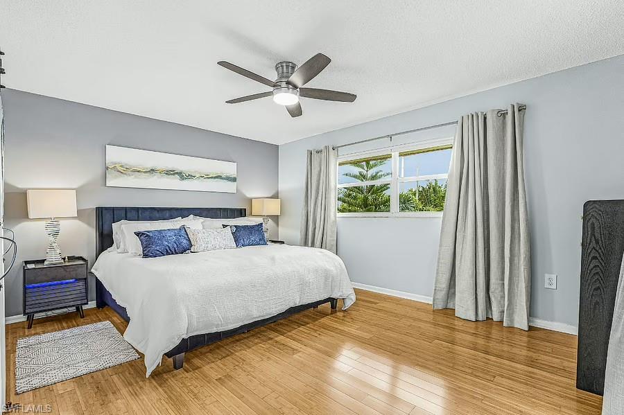 Wood-finish flooring, ceiling fan with integrated lighting, window with exterior landscape, and light gray wall paint
