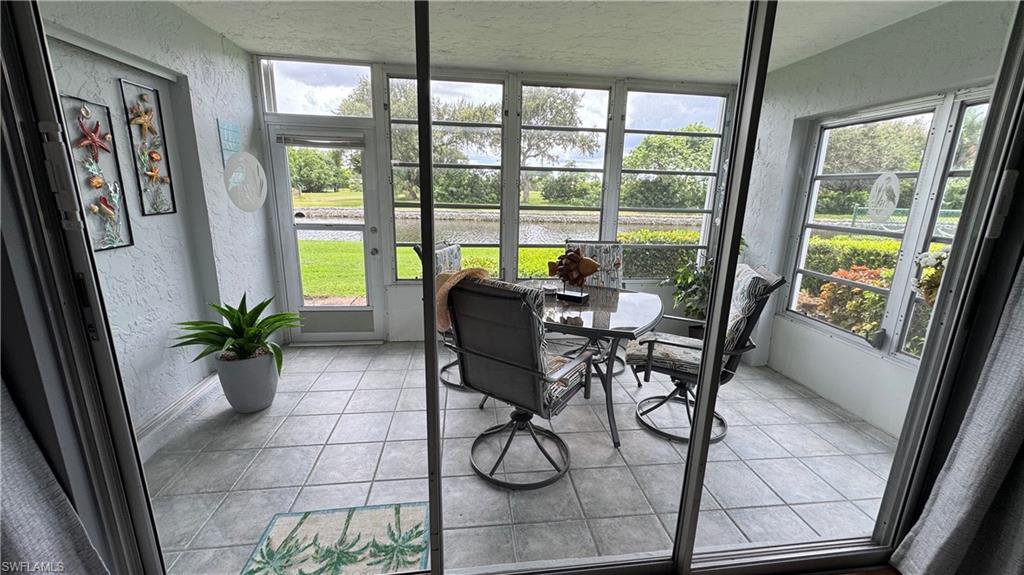 Enclosed Florida room featuring large windows, a tiled floor, and direct outdoor access