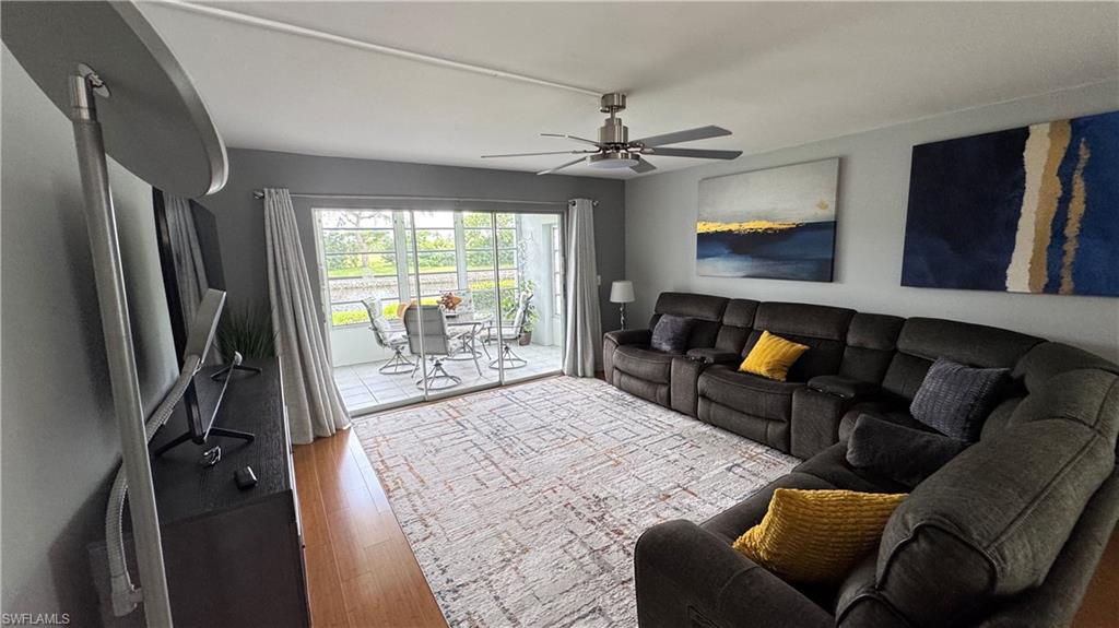 Wood-finish flooring, ceiling fan with brushed nickel finish, sliding glass doors, tiled outdoor patio, and outdoor dining set