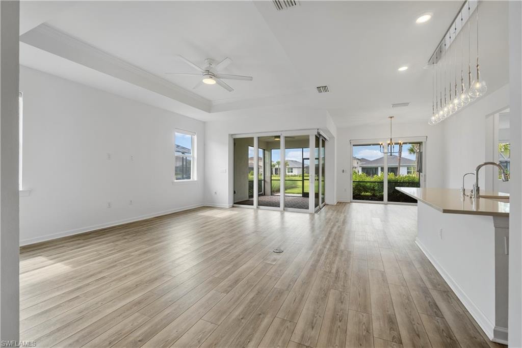 Tray ceiling, wood-finish flooring, ceiling fan, sliding glass doors, and recessed lighting