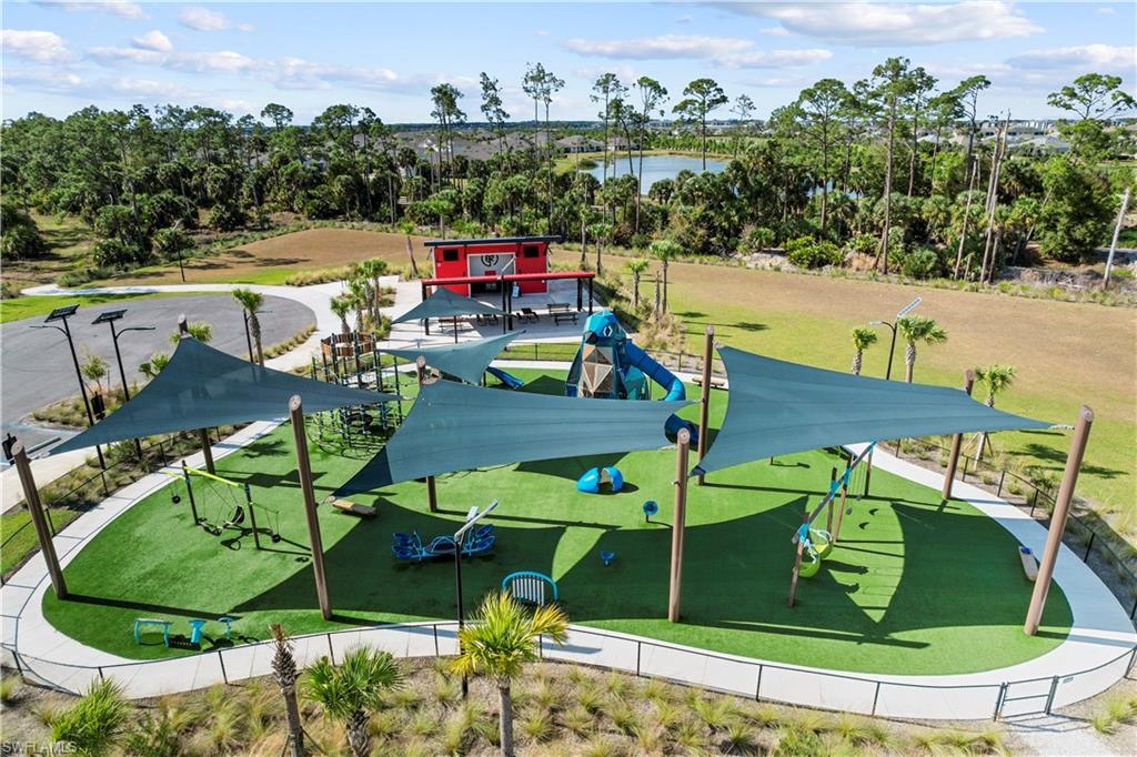 Expansive outdoor recreation area with artificial turf, multiple shade structures, and a playground
