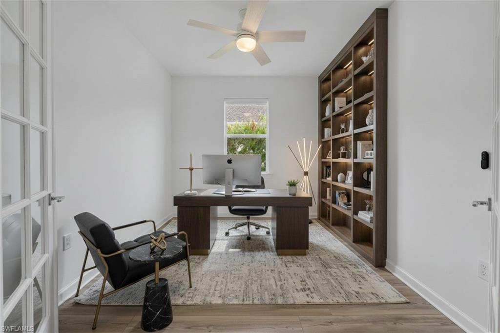 Built-in shelving with integrated lighting, wood-finish flooring, a ceiling fan, a window, and French doors