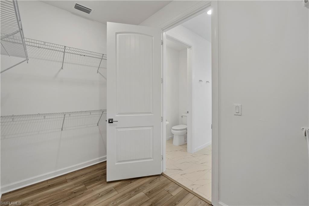 Walk-in closet with wire shelving and wood-finish flooring