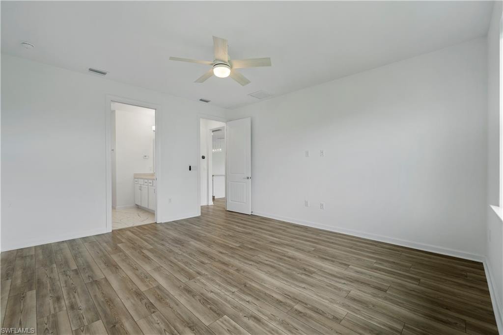 Wood-finish flooring, white walls, and a ceiling fan with integrated lighting