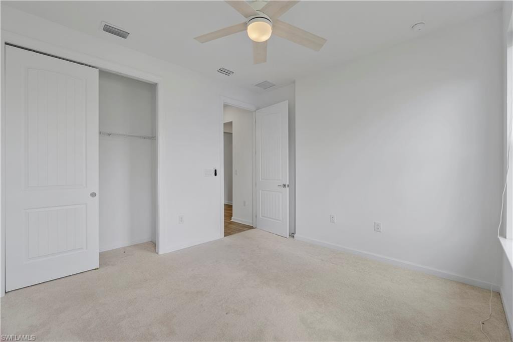 Wall-to-wall carpeting, ceiling fan with integrated lighting, paneled interior doors, and a built-in closet system