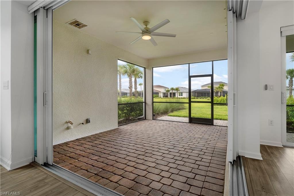 Screened outdoor area with paver flooring, a ceiling fan, and sliding glass doors