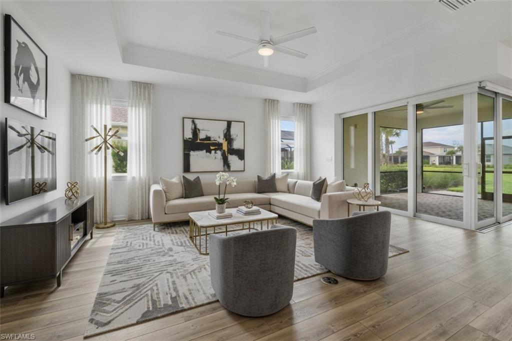 Tray ceiling featuring a ceiling fan, wood-finish flooring, and expansive sliding glass doors