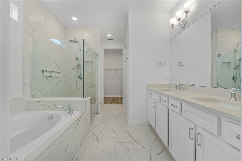 Dual vanity with integrated sinks, frameless glass shower enclosure, separate soaking tub, full-height mirror, and marble-look tile flooring
