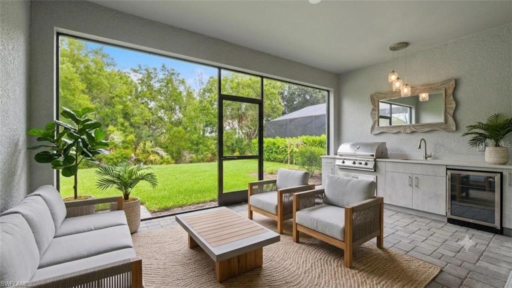 This covered and screened lanai extends the living space outdoors, creating the perfect setting for entertaining or unwinding in complete privacy. A built-in outdoor kitchen with grill, sink, beverage refrigerator, and generous counter space makes hosting effortless, while tranquil preserve views and tropical landscaping provide a peaceful backdrop for morning coffee, evening cocktails, or casual gatherings with friends and family.