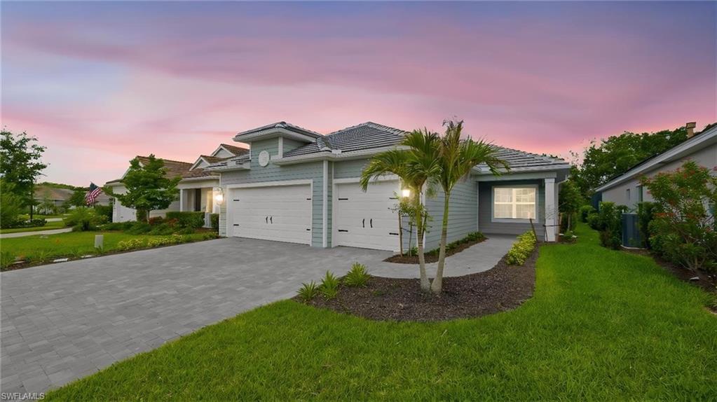 This stunning coastal-inspired residence makes a memorable first impression with its expansive paver driveway, three-car garage, and beautifully landscaped frontage framed by swaying palms. The soft glow of exterior lighting and the colorful Florida sunset create an inviting ambiance, while the upgraded elevation and meticulous curb appeal hint at the thoughtful design and luxury finishes waiting inside.