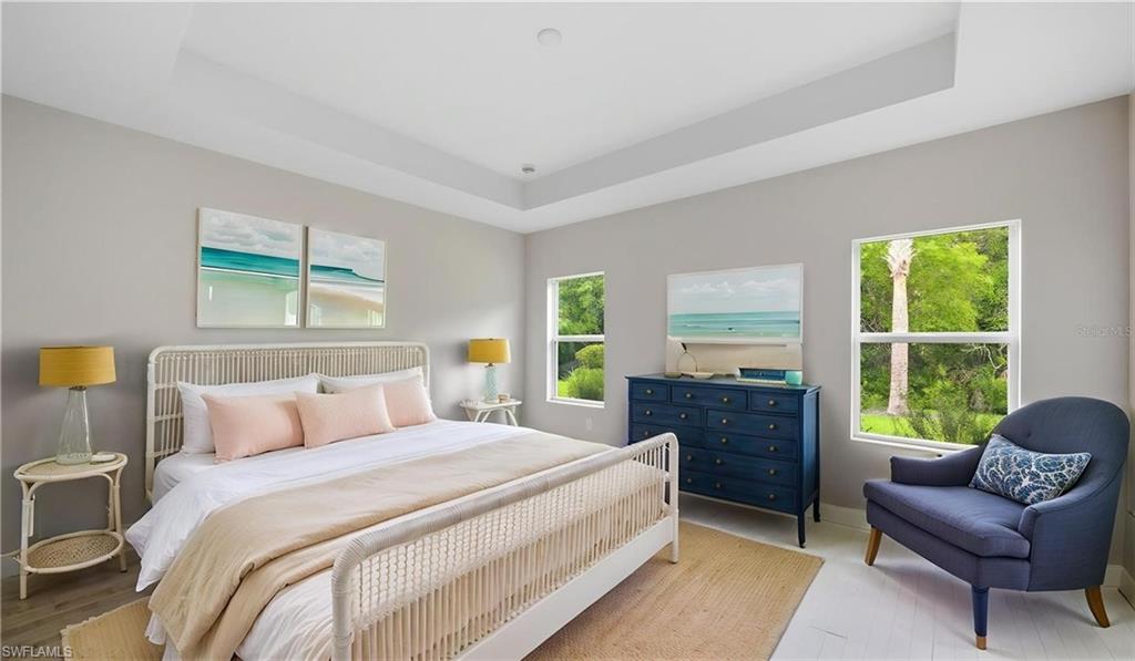 The spacious primary bedroom offers a calming escape with oversized windows that frame lush tropical greenery just beyond. Soft natural light fills the room throughout the day, while the tray ceiling adds architectural interest and volume. Generous proportions provide ample space for a sitting area, creating a private sanctuary to relax and recharge after enjoying all that Verandah has to offer.