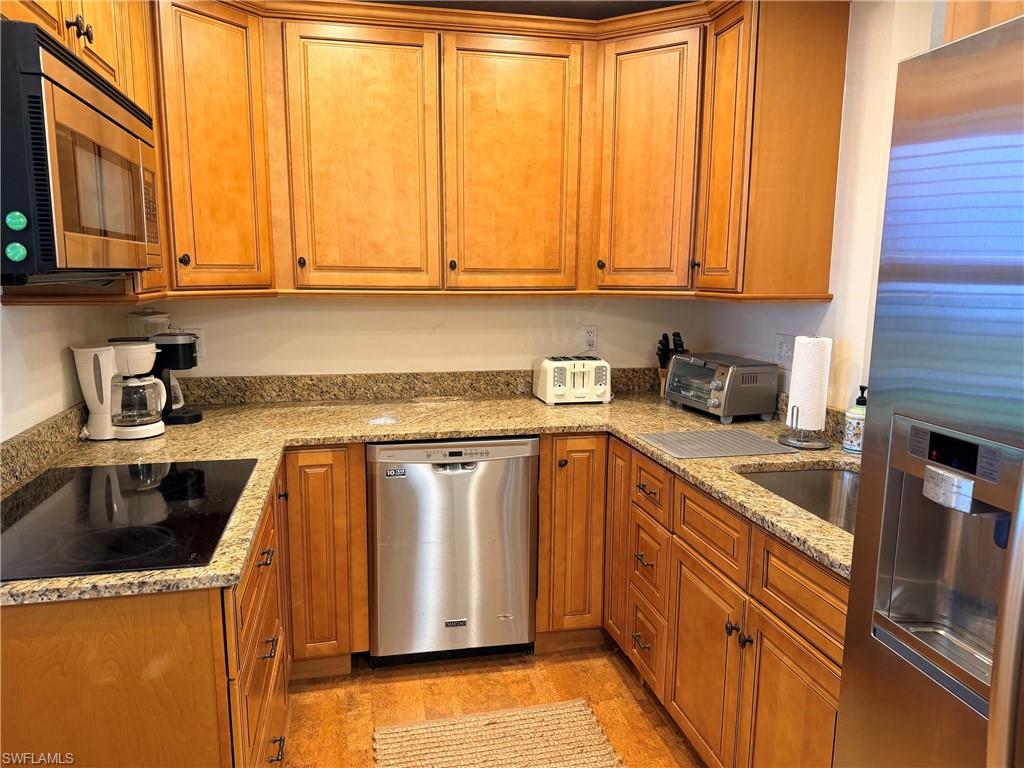 Wood-finish cabinetry, granite countertops, stainless steel appliances, built-in microwave, and an undermount sink