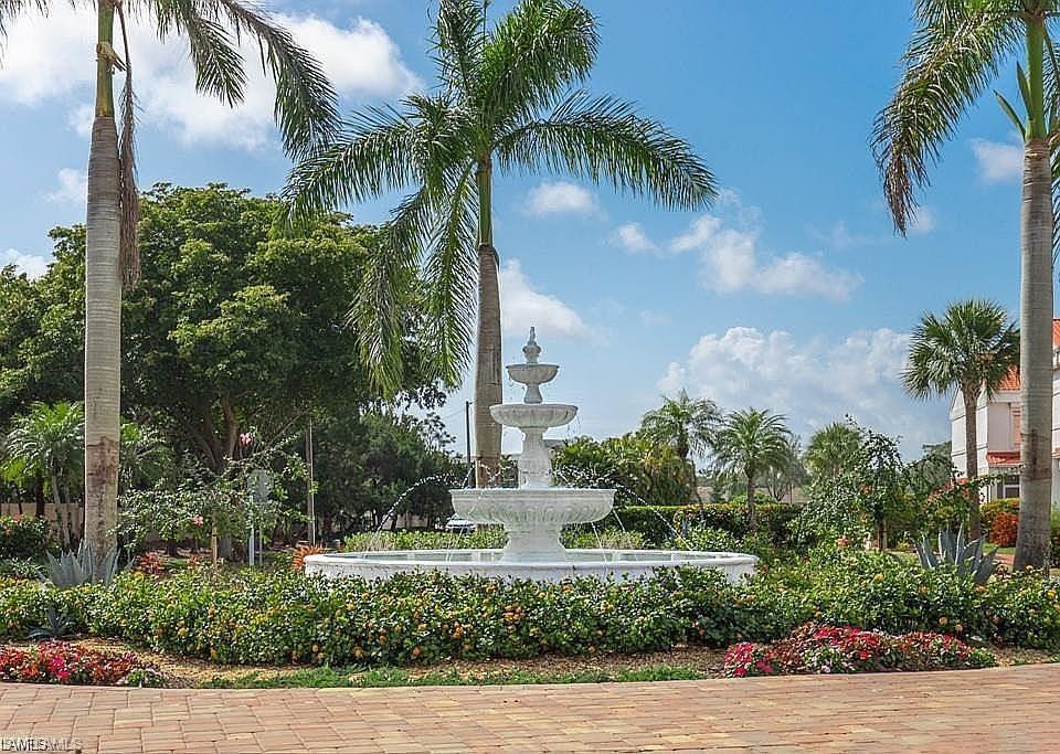 Three-tiered fountain centerpiece surrounded by lush landscaping and mature palm trees