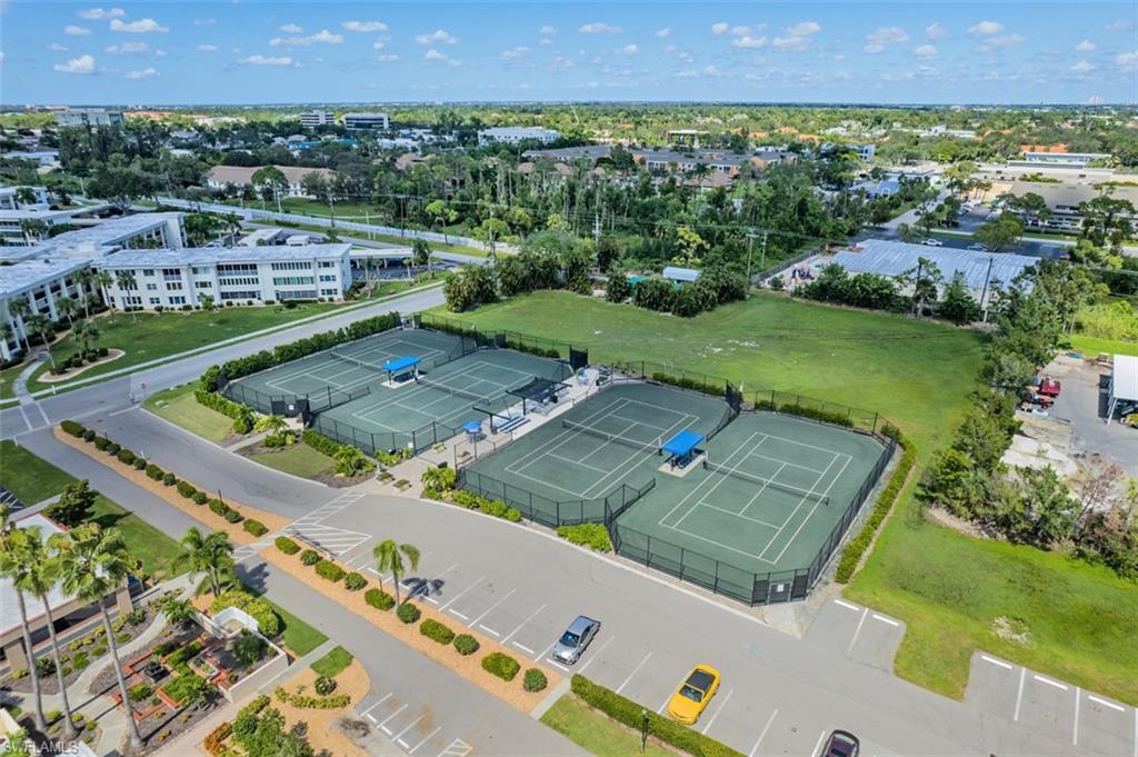 Multiple tennis courts with shaded seating areas and surrounding fencing