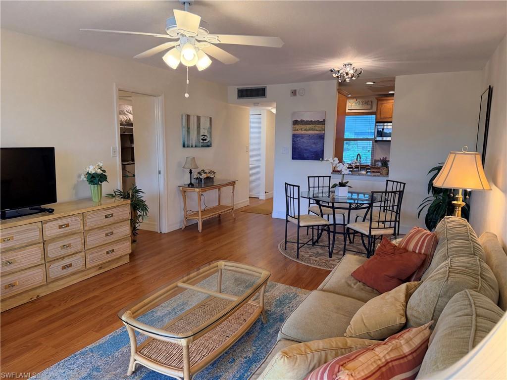 Hardwood-finish flooring, recessed lighting, ceiling fan with integrated lighting, and a pass-through window to the kitchen