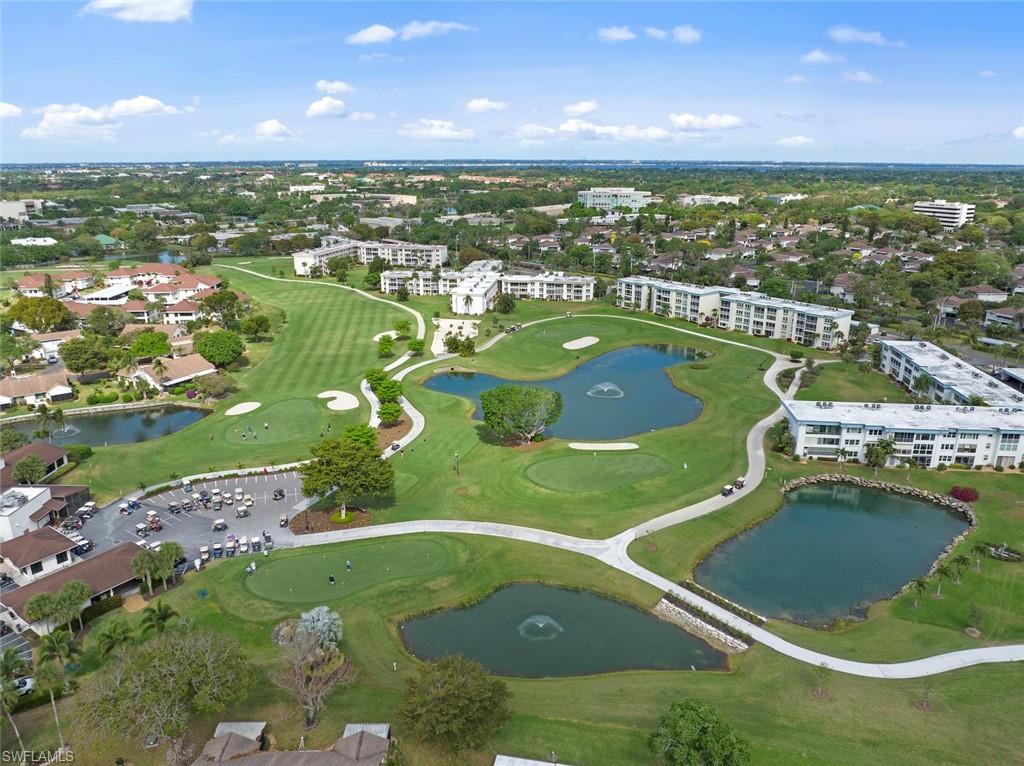 Expansive golf course setting featuring manicured greens, multiple water features with fountains, and surrounding residential buildings