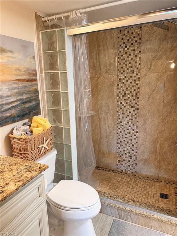 Walk-in shower with mosaic tile detailing, glass block partition, and sliding glass enclosure