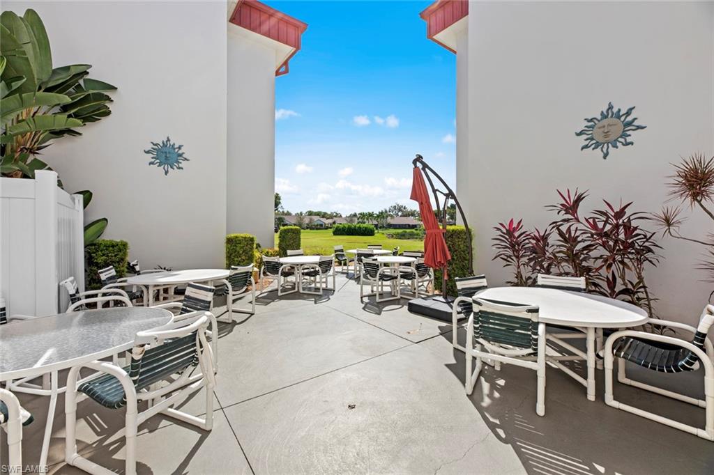 Expansive concrete patio area with white privacy fencing, surrounded by lush landscaping and decorative wall accents