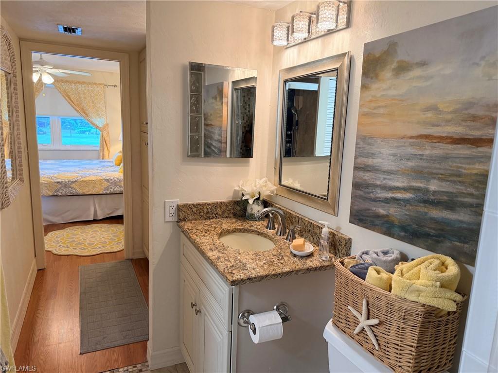 Vanity with granite-style countertop, undermount sink, and brushed nickel faucet