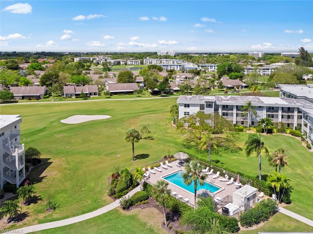 Expansive golf course frontage with a sand trap, mature palm trees, and an outdoor swimming pool with surrounding lounge chairs
