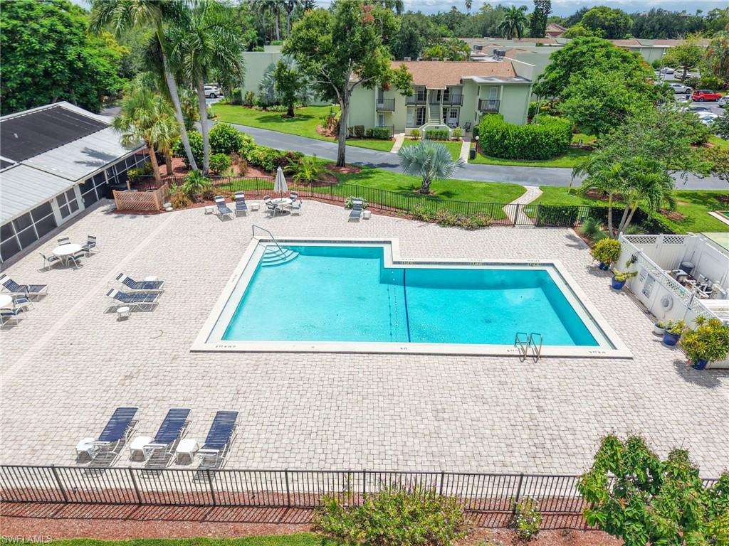 Spacious outdoor pool area featuring a large, irregular-shaped swimming pool, extensive paver deck, and surrounding lush landscaping