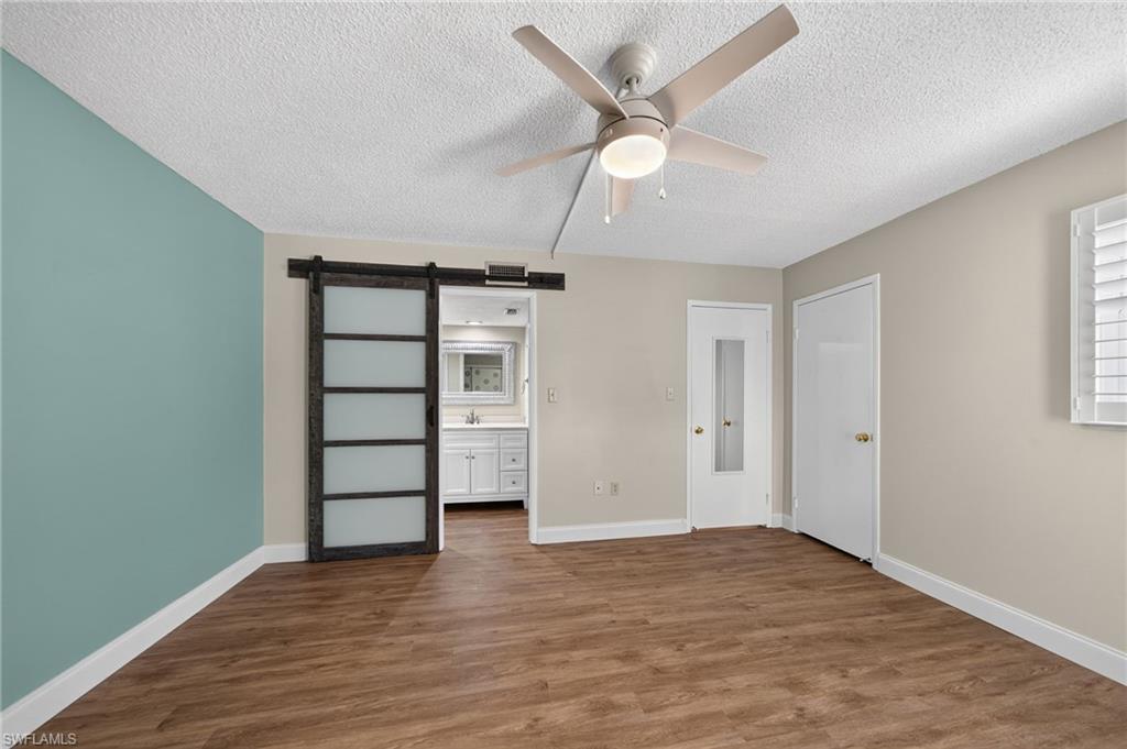 Primary bedroom, ceiling fan with integrated lighting, and a modern barn door