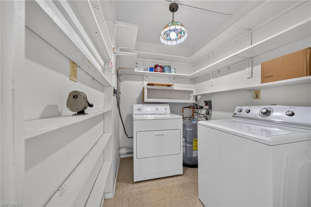 Integrated laundry appliances, extensive wall-mounted shelving, overhead lighting, and solid surface flooring