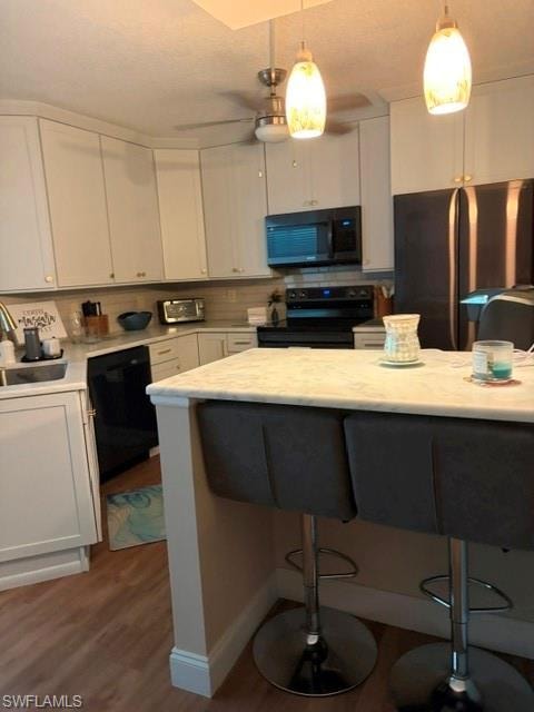 Kitchen featuring white shaker-style cabinetry, a light-toned backsplash, and a black appliance suite