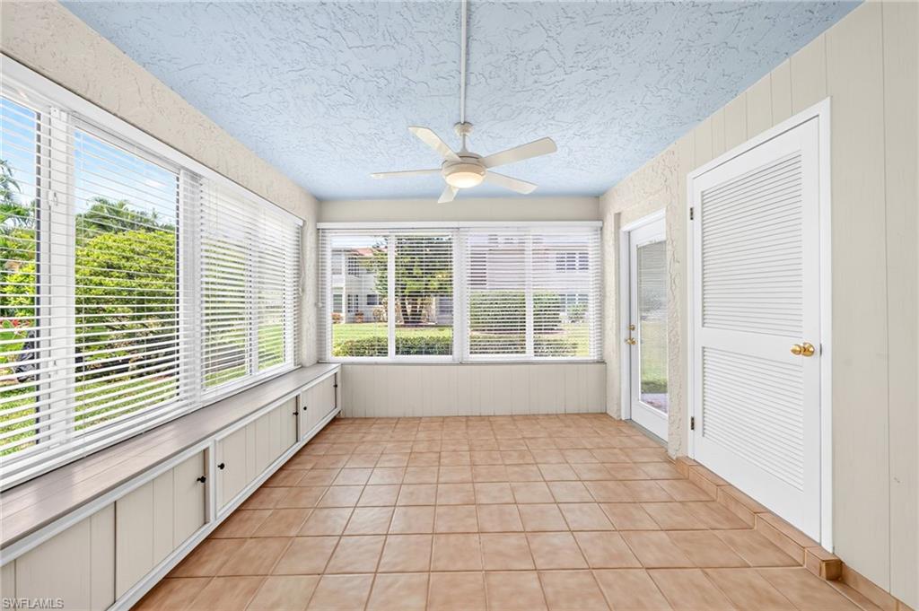 Bonus room, enclosed sunroom featuring multiple large windows, a built-in storage bench, ceramic tile flooring, a ceiling fan, and a louvered door