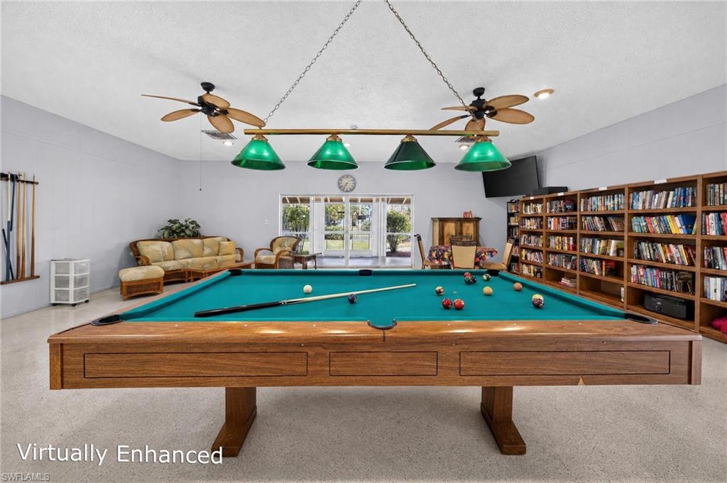 Recreation room featuring a pool table with a green felt surface, built-in shelving, and dual ceiling fans