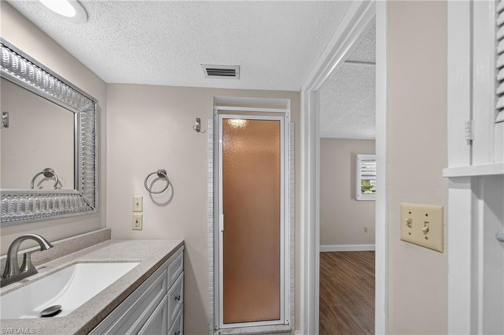 Vanity with integrated sink, brushed nickel faucet, framed mirror, and enclosed shower