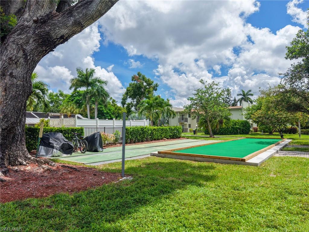 Lush green lawn with mature trees and a manicured hedge