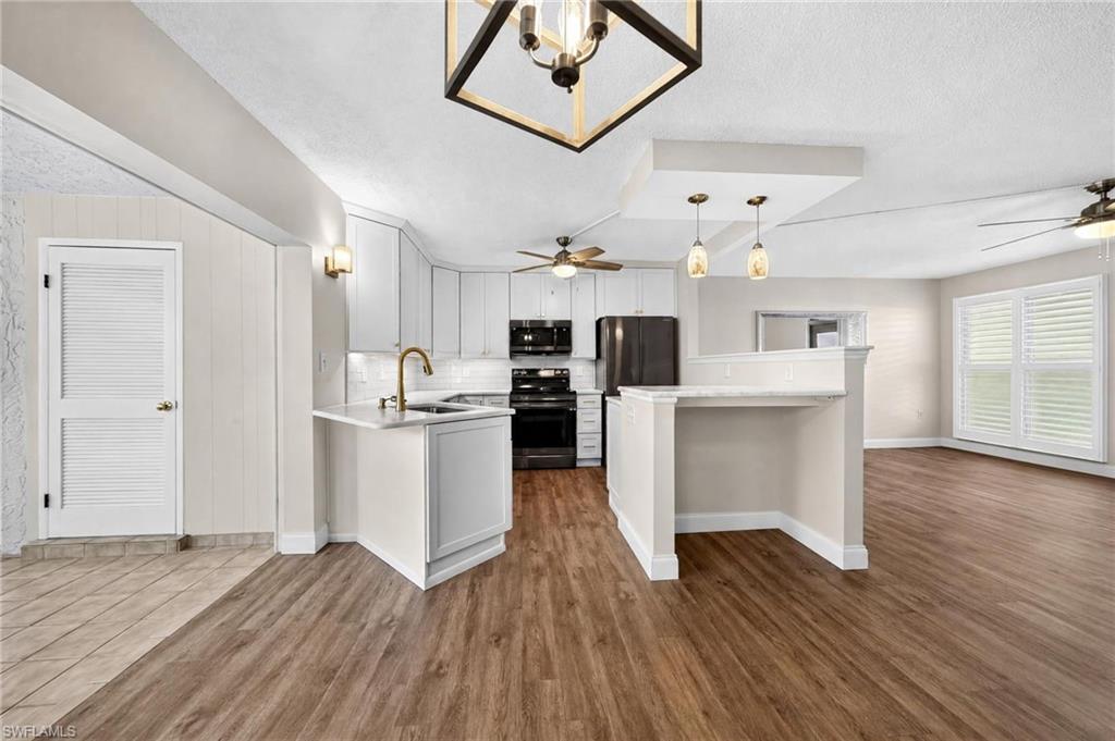 Modern kitchen featuring white cabinetry, a built-in sink, and black appliances