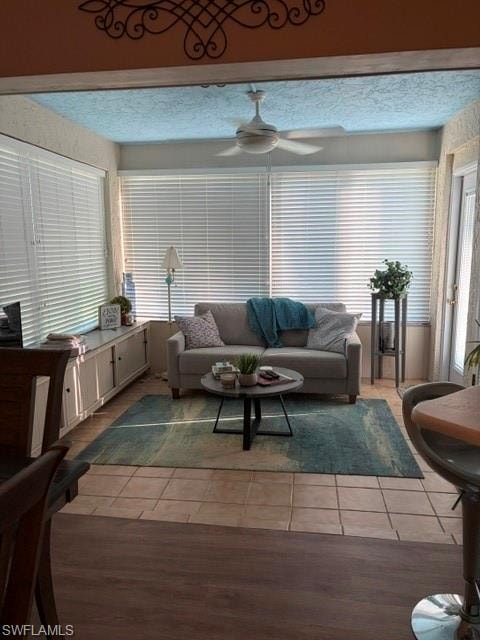 Sunroom featuring extensive window coverage, a ceiling fan, tiled flooring, and built-in white cabinetry