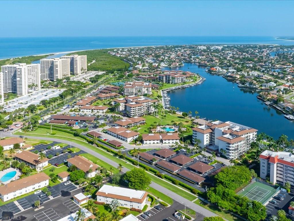 Coastal community featuring a winding waterway, residential structures, a tennis court, and multiple swimming pools