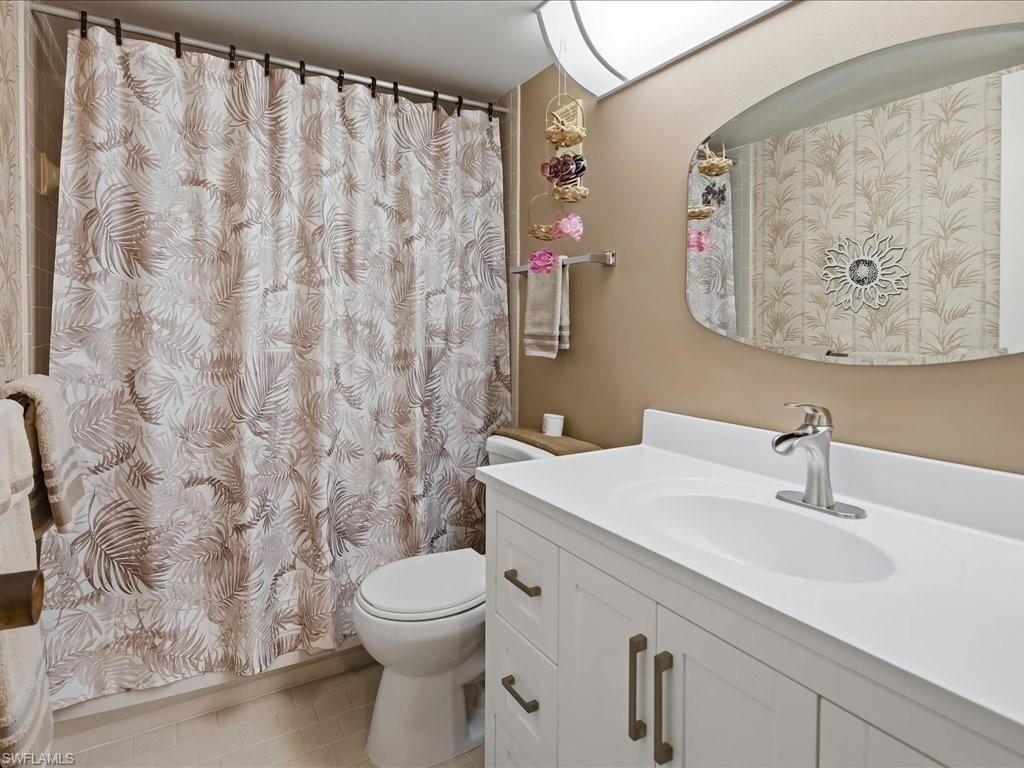 White vanity with integrated sink, chrome faucet, and bronze hardware