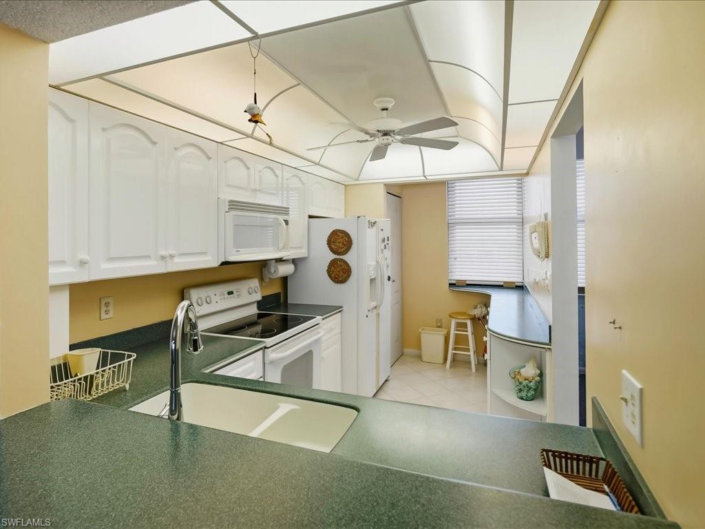 Kitchen featuring white cabinetry, a built-in microwave, an electric range, a ceiling fan, and a double basin sink