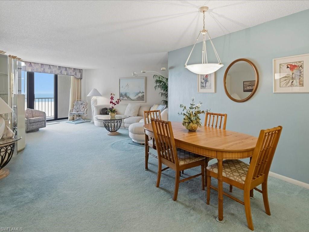 Open-concept living and dining areas with expansive floor-to-ceiling windows, a wood dining table, and a contemporary pendant light fixture