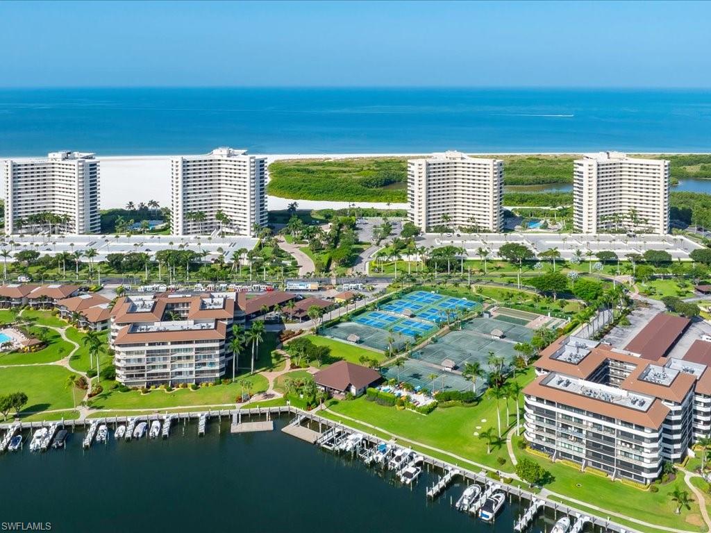 Coastal property with multiple high-rise and mid-rise residential buildings, private boat docks, tennis courts, and manicured green spaces