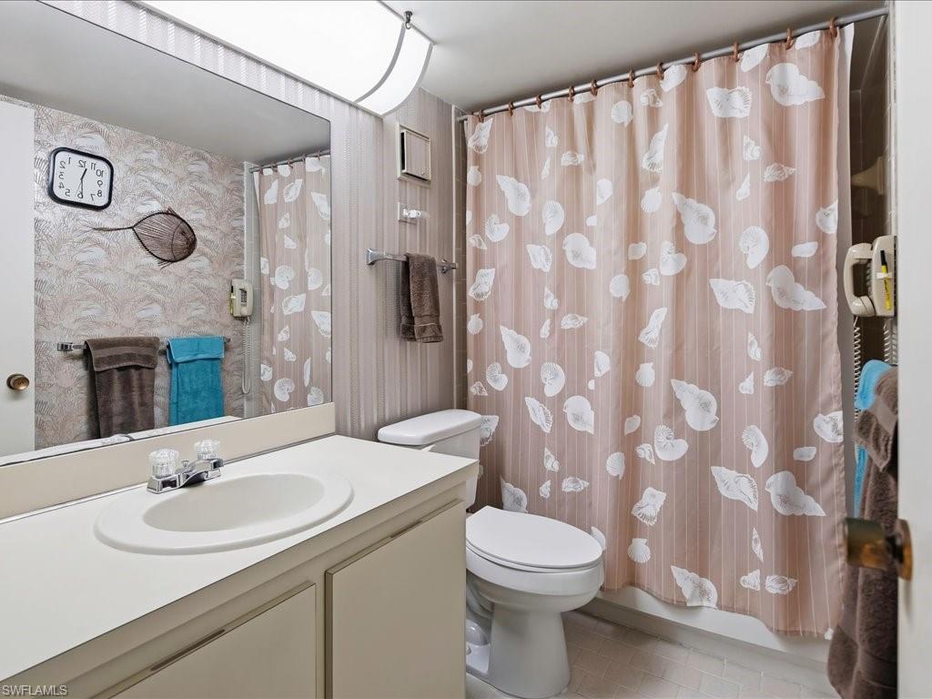 Bathroom featuring an integrated countertop sink, under-sink cabinetry, a toilet, and a shower area